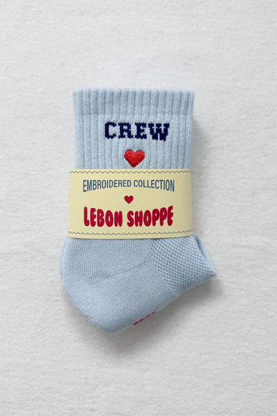 Light blue sock with 'CREW' text and heart design, on a light gray background